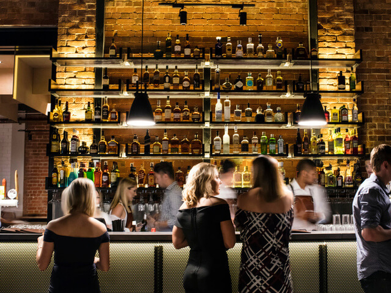Group of people standing at bar of Headricks Lane drinking venue