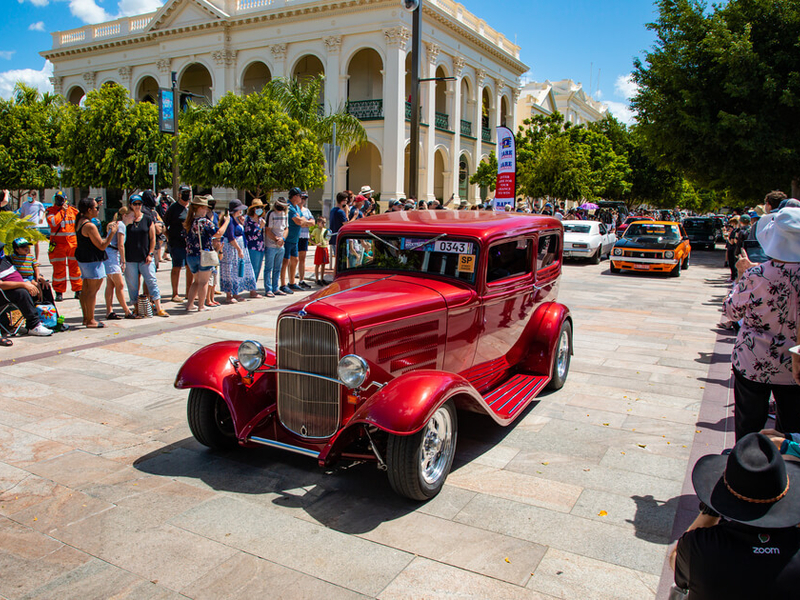 Bright red hot rod classic car on Quay Street with crowd watching